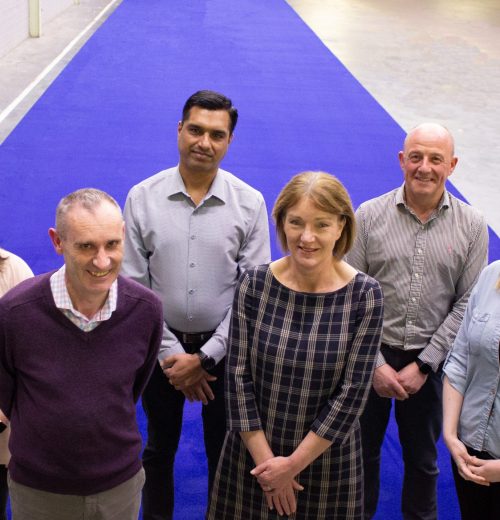 Pictured with the Royal Blue carpet for the Coronation of King Charles III are Nick Coburn, Group Managing Director, and Joyce McIvor, UK and Ireland Contract Sales Director, with representatives from different departments at Ulster Carpets (back row, from left) Hannah Topping, Manu Thomas, Andrew Carson, and Sarah Moffett.