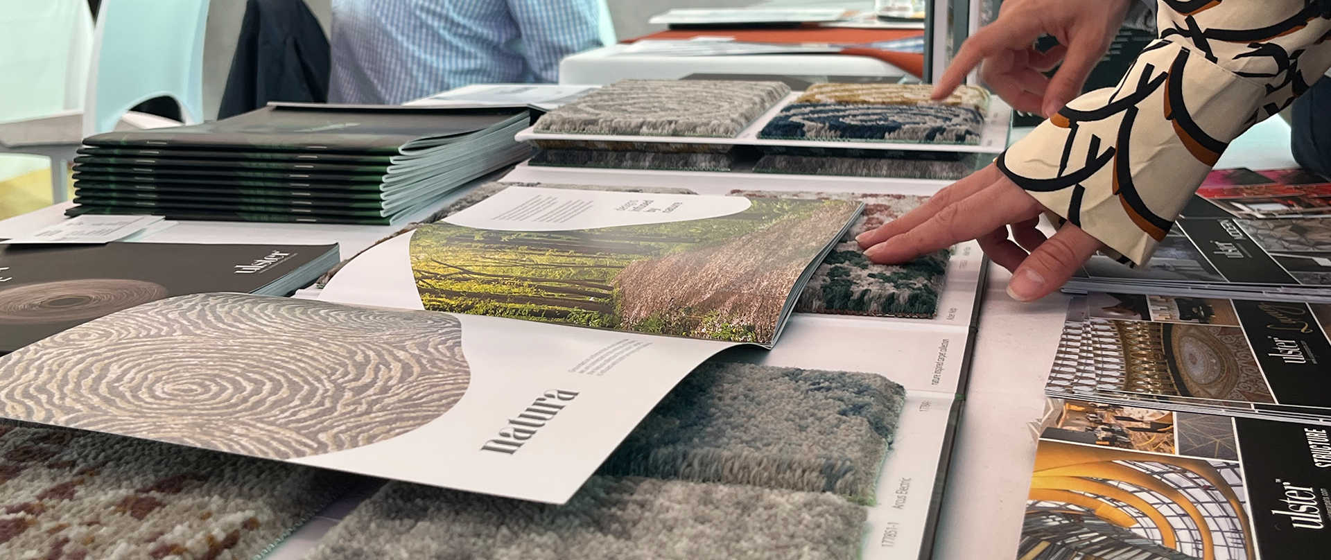 A customer looking through carpet sample books and brochures from Ulster Carpets.