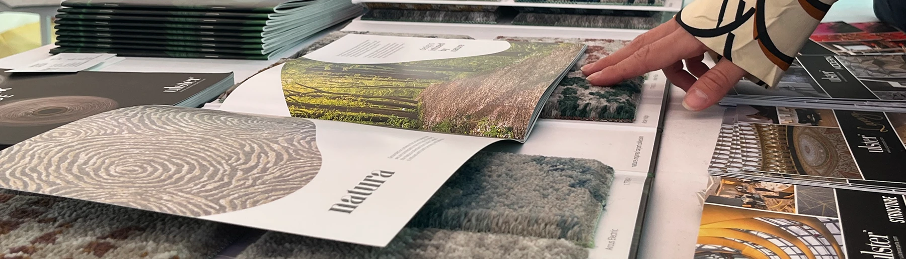 A customer looking through carpet sample books and brochures from Ulster Carpets.