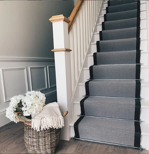 grey stain runner with black bindings on white stairs